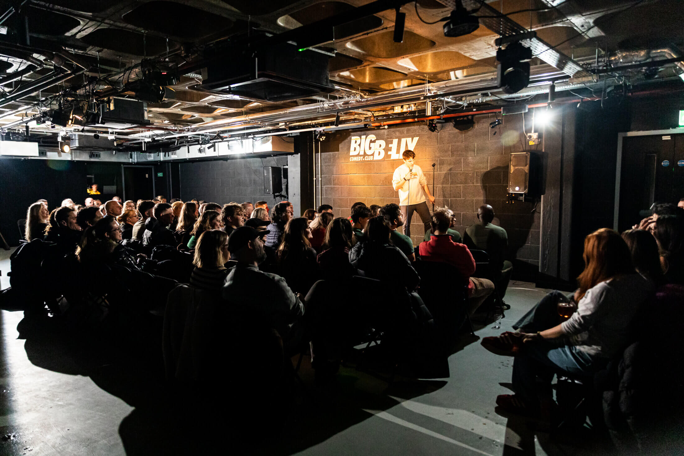 A performer facing a packed audience at Big Belly Comedy Club